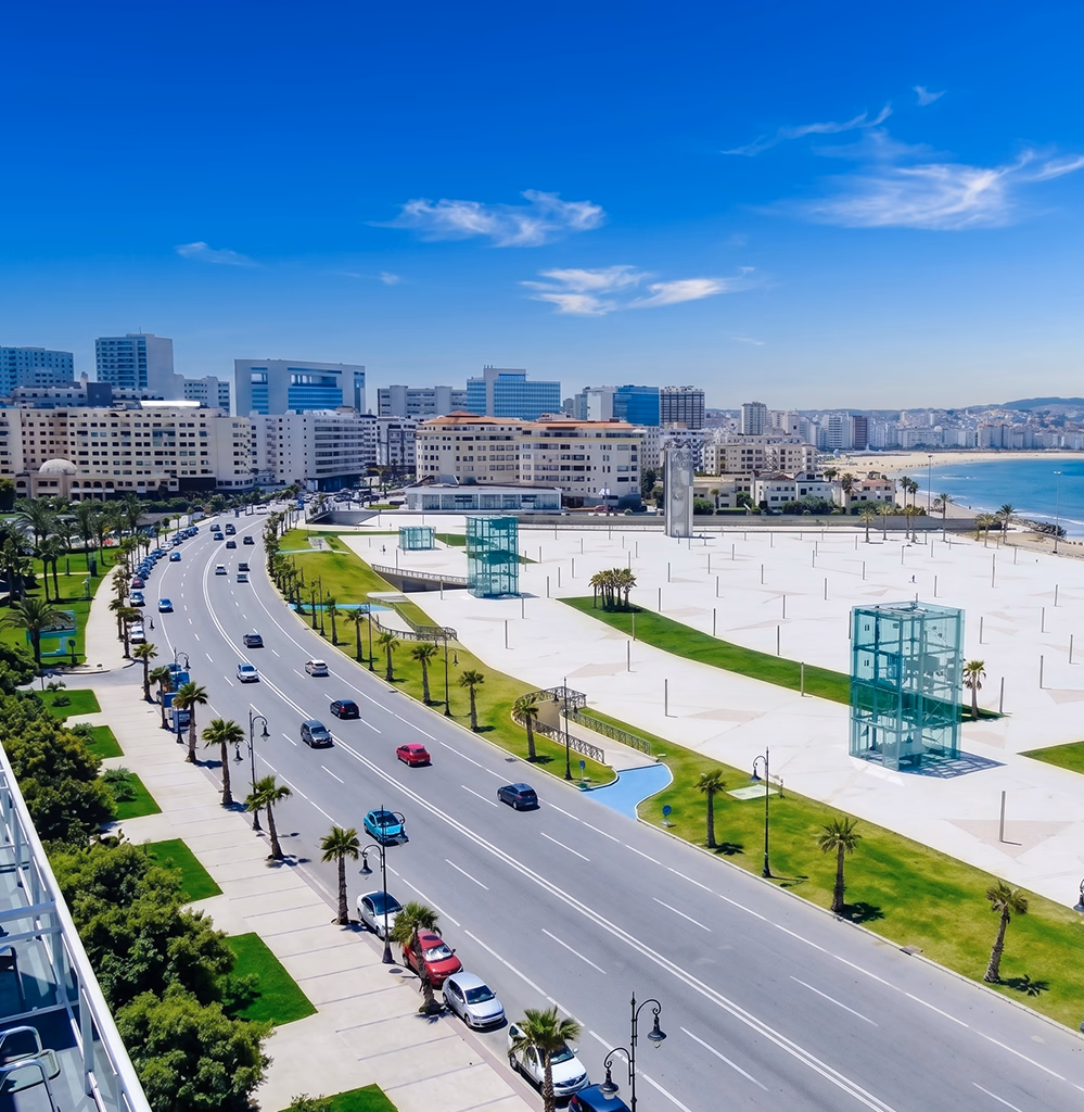 Agence immobilière à Tanger — vue aérienne du boulevard Mohammed VI et de la corniche, palmiers et front de mer, Conciera opère achat, vente et investissement immobilier dans le secteur le plus prisé de Tanger